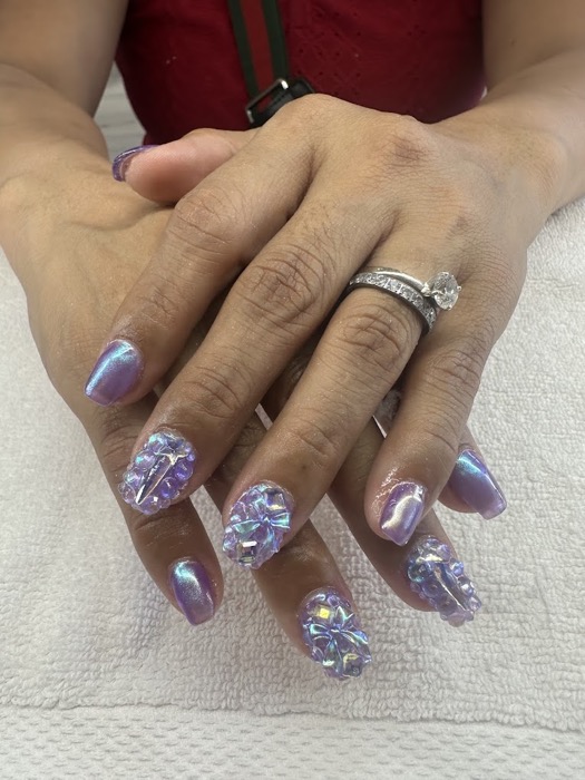 Close-up of a manicurist painting delicate, fine black lines on a client's nude nail.